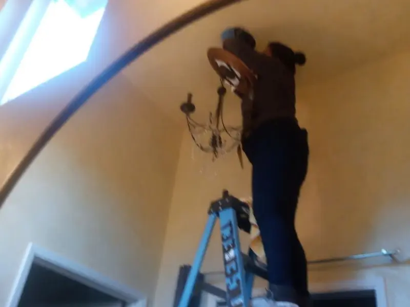 Electrician installing a chandelier in a Winterville residence